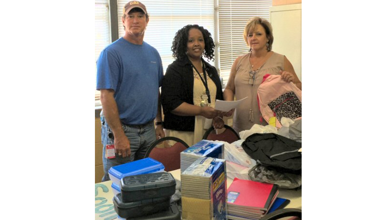 Mike Kyle, senior planner/scheduler, left, and Mary James, administrative assistant, right, deliver supplies to Amy Fleming, school secretary.