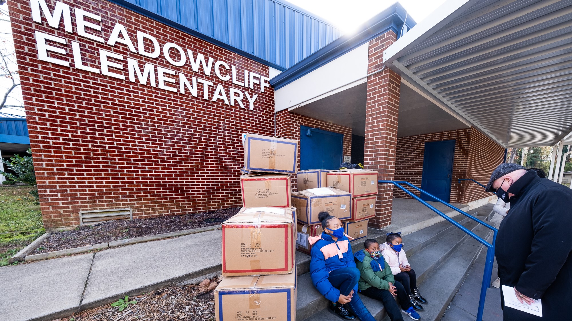 Three students at Meadowcliff Elementary visit with Superintendent Mike Poore after receiving their new coats. 