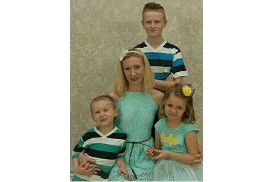 Photo of Larissa with her children: youngest son, Elijah, daughter, Emma Jean, and oldest son, Connor, standing in back.