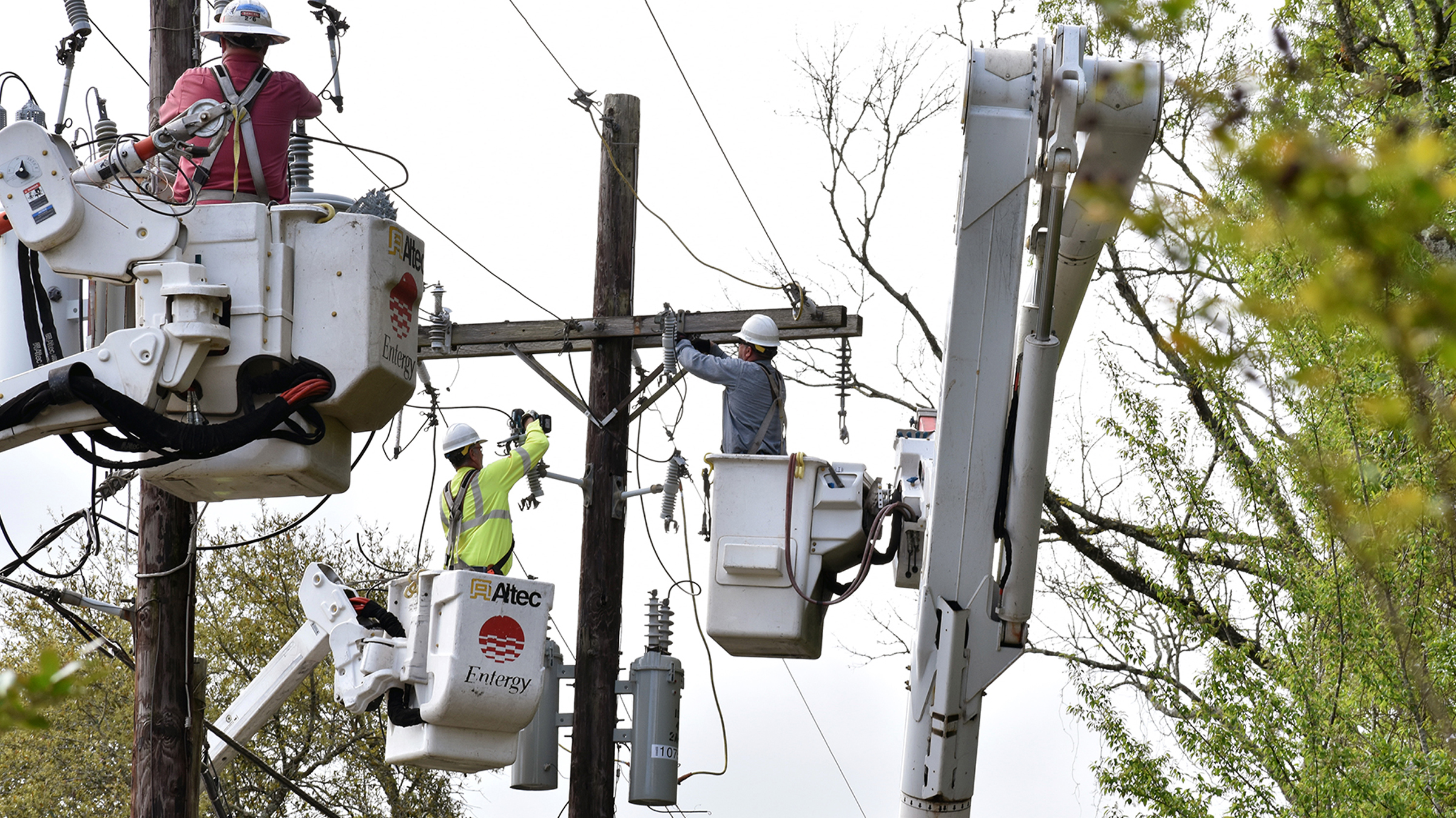 Distribution line workers install new equipment and power lines on utility poles in Tangipahoa Parish.