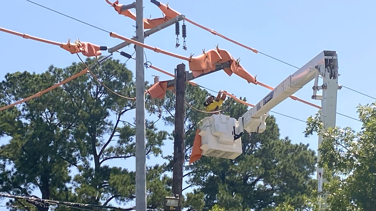 A lineworker applies covers a part of a power line during the installation of a new smart device near the corner of Jefferson Highway and Highland Road in Baton Rouge. 